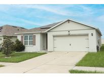 Tan house with brown accents, solar panels, and a two-car garage at 277 Ludisia Loop, Davenport, FL 33837