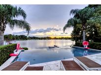 Stunning infinity pool overlooking a lake at sunset at 1010 Strathmore Dr, Orlando, FL 32806