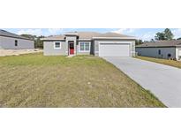 Newly constructed home with gray exterior, red door, and two-car garage at 486 Marion Oaks Blvd, Ocala, FL 34473