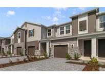 Modern townhome with gray siding, two-car garage, and landscaped front at 707 Southern Edge Way, Sanford, FL 32771