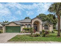 Tan one-story house with green garage door and landscaped yard at 16208 Magnolia Hill St, Clermont, FL 34714