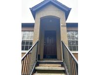 Exterior view of condo building entrance with stairs and brown door at 6312 Raleigh St # 513, Orlando, FL 32835