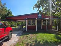 Red house with carport, mature landscaping, and a spacious yard at 10 Mccarthy Ave, Frostproof, FL 33843