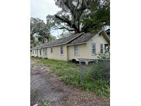 Long, single-story yellow house with multiple windows and a chain link fence at 2800 Magnolia Ave, Sanford, FL 32773