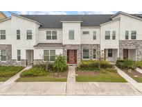 Modern townhome exterior with stone and white siding, and a red door at 2163 Copper Bell Pl, Kissimmee, FL 34747
