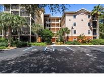 Exterior view of a condo building with parking and landscaping at 9055 Treasure Trove Ln # 206, Kissimmee, FL 34747