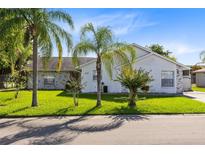 One-story home with white exterior, lush lawn, and palm trees at 148 Merida Dr, Kissimmee, FL 34743
