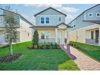 Two-story light blue house with brick walkway, landscaping, and a front porch at 11960 Bracco St, Winter Garden, FL 34787