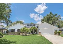 White house with a brick facade, two-car garage and palm trees at 7904 Dunstable Cir, Orlando, FL 32817