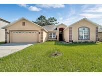 House exterior showing a tan two-story home with a two-car garage at 468 Acacia Tree Way, Kissimmee, FL 34758