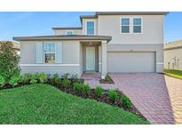 Two-story house with gray siding, brick driveway, and landscaping at 2462 Leeds St, Haines City, FL 33844