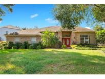 Brick house with a manicured lawn, red door, and palm trees at 1434 Hidden Meadow Way, Apopka, FL 32712