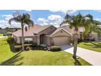 Tan one-story house with two palm trees in front and a two car garage at 4070 Island Lakes Dr, Winter Haven, FL 33881
