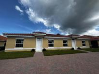 Front view of three-unit building with yellow exterior and tile roofs at 1652 Cumin Dr, Poinciana, FL 34759