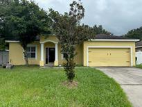 Charming yellow house with a two-car garage and a manicured lawn at 5320 Song Sparrow Ct, Lakeland, FL 33811