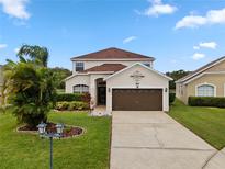 Two-story house with a brown garage door and landscaped yard at 957 Whispering Cypress Ln, Orlando, FL 32824