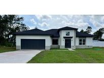 Modern house exterior with a two-car garage and a well-manicured lawn at 2572 Sw 159Th Ln, Ocala, FL 34473