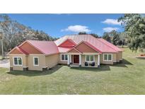 One-story home with a red metal roof, surrounded by lush greenery at 14742 Sw 4Th Ave, Ocala, FL 34473