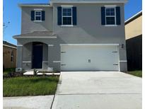 Two-story house with gray siding, white garage door, and blue shutters at 2924 Waterlily Way, Poinciana, FL 34759