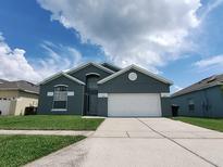 Two-story house with gray exterior, white garage door, and green lawn at 714 Hacienda Cir, Kissimmee, FL 34741