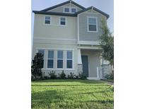 Two story home with light beige siding and a green lawn at 15102 Stuttgart Aly, Winter Garden, FL 34787