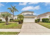 Two-story house with a two-car garage and palm trees at 145 Cork Way, Davenport, FL 33897
