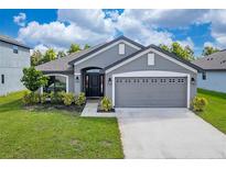 Gray house with a two-car garage and landscaping at 220 Bergamot Loop, Davenport, FL 33837