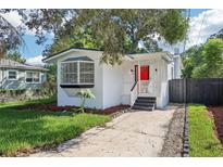 Adorable bungalow with a red door, freshly landscaped yard, and a paved driveway at 1815 Larkin Ave, Orlando, FL 32812