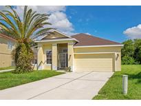 Charming yellow house with a two car garage and palm tree at 1033 Hacienda Cir, Kissimmee, FL 34741