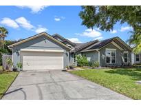 Gray house with a white garage door, landscaping, and a driveway at 1451 Twin Rivers Blvd, Oviedo, FL 32766