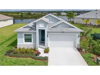 Single-story home with a white garage door, landscaped yard, and a lake view at 8632 Bridgeport Bay Cir, Mount Dora, FL 32757