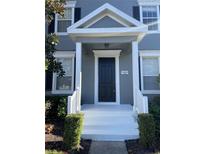 Gray house exterior with a white porch, black front door, and landscaping at 14460 Clarkson Dr, Orlando, FL 32828