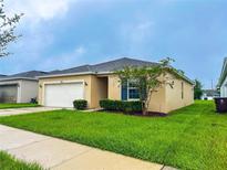 Tan one-story house with a two-car garage and landscaped yard at 515 Taft Dr, Davenport, FL 33837