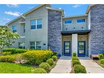Modern two-story townhome with gray siding, stone accents, and blue doors at 740 Pebble Beach Dr, Davenport, FL 33896