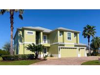 Two-story house with light green exterior, two-car garage, and palm trees at 10126 Lake Miona Way, Oxford, FL 34484