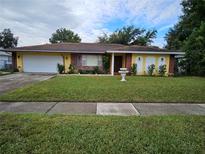 Ranch-style home with a well-maintained lawn and a two-car garage at 7104 Scruboak Ln, Orlando, FL 32818