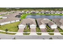 Aerial view of three attached homes with two-car garages, and a shared pond at 2952 Cherry Blossom Loop, Saint Cloud, FL 34771