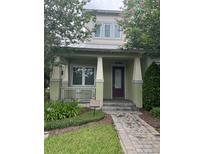 Green two-story home with a purple door and landscaped walkway at 8282 Tavistock Lakes Blvd, Orlando, FL 32827