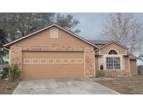 Tan house with a two-car garage and solar panels at 2618 Coventry Ln, Ocoee, FL 34761
