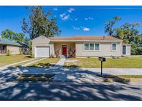 Tan house with red door, two-car driveway, and landscaped yard at 112 S Moss St, Leesburg, FL 34748