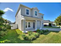 Two-story house with gray siding, two-car garage, and landscaped front yard at 1501 Woodlark Dr, Haines City, FL 33844