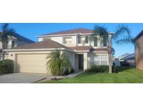 Two-story house with a beige garage door and palm trees at 115 Canna Dr, Davenport, FL 33897