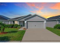 One-story home with gray siding, two car garage and landscaped yard at 653 Persian Dr, Haines City, FL 33844