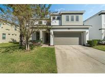 Two-story house with gray siding, a two-car garage, and a well-manicured lawn at 4511 Monado Dr, Kissimmee, FL 34746