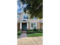 Tan two-story townhome with teal front door and landscaped entryway at 15578 Murcott Blossom Blvd, Winter Garden, FL 34787