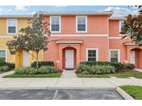 Two-story townhome with orange and yellow exterior, landscaping, and parking at 3004 Bird Of Paradise Ln, Kissimmee, FL 34747