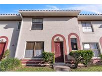 Tan two-story townhouse with red door and landscaping at 6295 River Run Pl # 199, Orlando, FL 32807