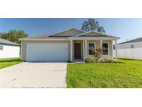 Beige house with a white garage door and landscaping at 231 Begonia Ln, Kissimmee, FL 34759