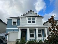 Two-story house with blue exterior, white garage door, and a covered front porch at 2104 Fleming Mist Pl, Kissimmee, FL 34747