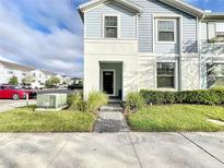Two-story townhome with gray siding, a brick walkway, and landscaping at 8931 Sydney Ave, Kissimmee, FL 34747